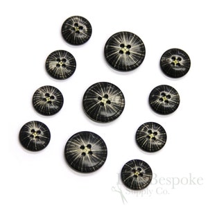 May include: A set of ten black and white buttons with a starburst design. The buttons have four holes and are made of a natural material.