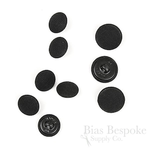 Peut inclure: Plusieurs boutons noirs recouverts de tissu à texture côtelée sont disposés sur un fond blanc. Certains boutons ont une tige à l'arrière. Les boutons sont ronds et ovales. Le texte "Bias Bespoke Supply Co." est visible.