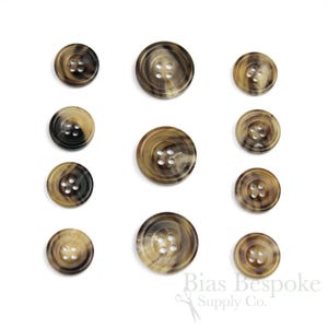 May include: Set of ten brown and black horn buttons with four holes each. The buttons are arranged in two rows of five.