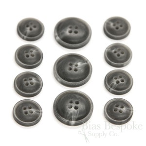 May include: A set of ten gray and white marbled buttons with four holes each. The buttons are arranged in three rows on a white background.