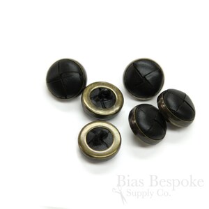 May include: Six black leather buttons with a brass rim. The buttons have a cross-stitch pattern.
