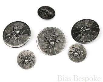 May include: Six silver-toned spider buttons with a web design. The buttons are different sizes and are arranged in a semi-circle on a white background. Bias Bespoke Supply Co. is printed in black at the bottom of the image.