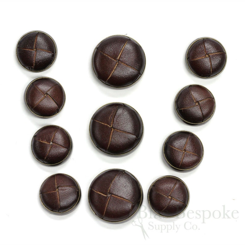 May include: Assortment of brown leather buttons with a cross stitch design. The buttons are various sizes.