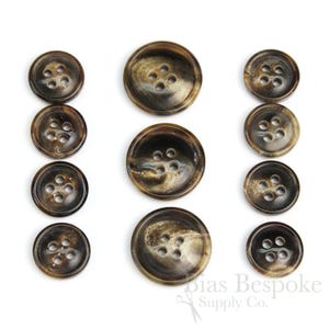 May include: Set of ten brown horn buttons with a mottled pattern. The buttons are in various sizes and have four holes each.