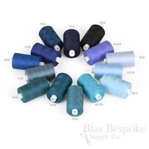 May include: A variety of spools of thread in shades of blue, teal, and gray. The spools are arranged in a circle on a white background. The numbers 290, 358, 756, 298, 999, 762, 770, 450, 350, 4130, 4160, 3270, 262, and 260 are printed on the spools. The text "Bias Bespoke Supply Co." is printed below the spools.