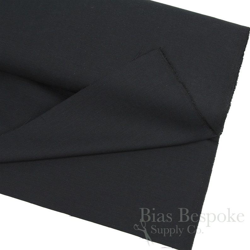 May include: Black fabric folded in half. The fabric is smooth and has a slight sheen. The text "Bias Bespoke Supply Co." is visible in the bottom right corner of the image.