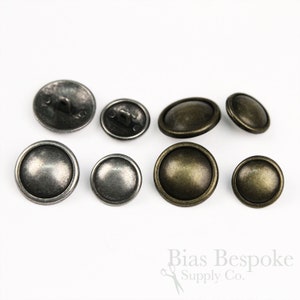 May include: Assortment of eight metal buttons in two finishes: antique silver and antique brass. The buttons are round with a raised dome and a shank on the back.