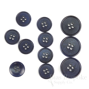 May include: A set of ten navy blue plastic buttons with five holes each. The buttons are arranged in a row and a column.