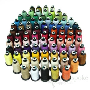 May include: A large collection of spools of thread in various colors, arranged in a circle. The spools are all the same size and shape, and they are all wound with thread. The thread is a variety of colors, including red, blue, green, yellow, and orange. The spools are arranged in a circle, with the colors of the thread gradually changing from one spool to the next. The spools are all labeled with the color of the thread.