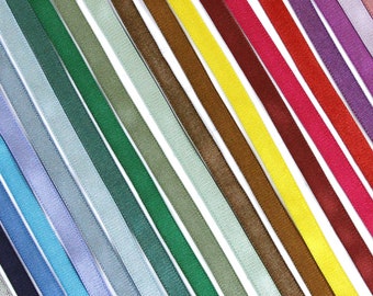 May include: A collection of narrow fabric ribbons arranged in parallel diagonal lines, featuring a spectrum of colors including silver, navy, blue, light blue, lavender, green, olive, mint, brown, yellow, maroon, red, magenta, purple, and pink.