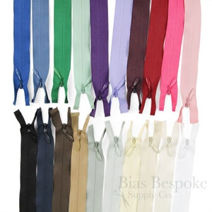 May include: Assortment of 20 zipper tapes in various colours, including navy blue, brown, beige, light green, purple, lavender, maroon, red, and pink. The zippers are all closed and laid out in two rows.