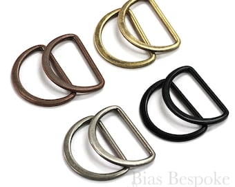May include: Four pairs of D-rings in different finishes: antique brass, antique copper, antique nickel, and black. Each D-ring is made of metal and has a smooth, polished finish.