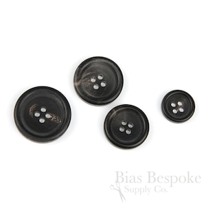 May include: Set of four black horn buttons with four holes each. The buttons are different sizes and have a marbled pattern.