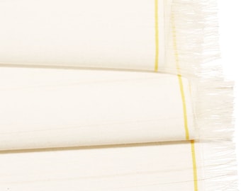 May include: White table runner with a yellow stripe down the center and a fringe on the edge.