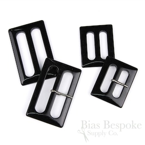 May include: Three black plastic belt buckles with silver metal clasps. The buckles are rectangular with rounded corners and have two parallel slots for the belt to pass through.