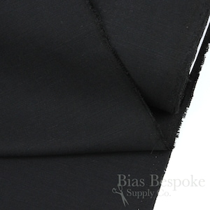 May include: Black fabric with a subtle texture. The fabric is folded in half and the edges are visible. The fabric is labelled "Bias Bespoke Supply Co."