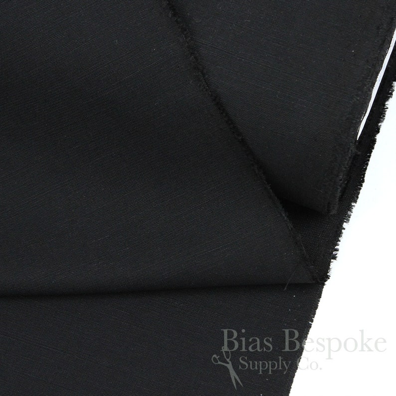 May include: Black fabric with a subtle texture. The fabric is folded in half and the edges are visible. The fabric is labelled "Bias Bespoke Supply Co."
