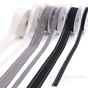 Puede incluir: Cinco carretes de cinta con diferentes colores y patrones. La cinta es blanca, gris, negra y tiene un patrón de puntos blancos. La cinta está sobre un fondo blanco.
