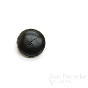 May include: Black leather button with a woven design and a brass rim.