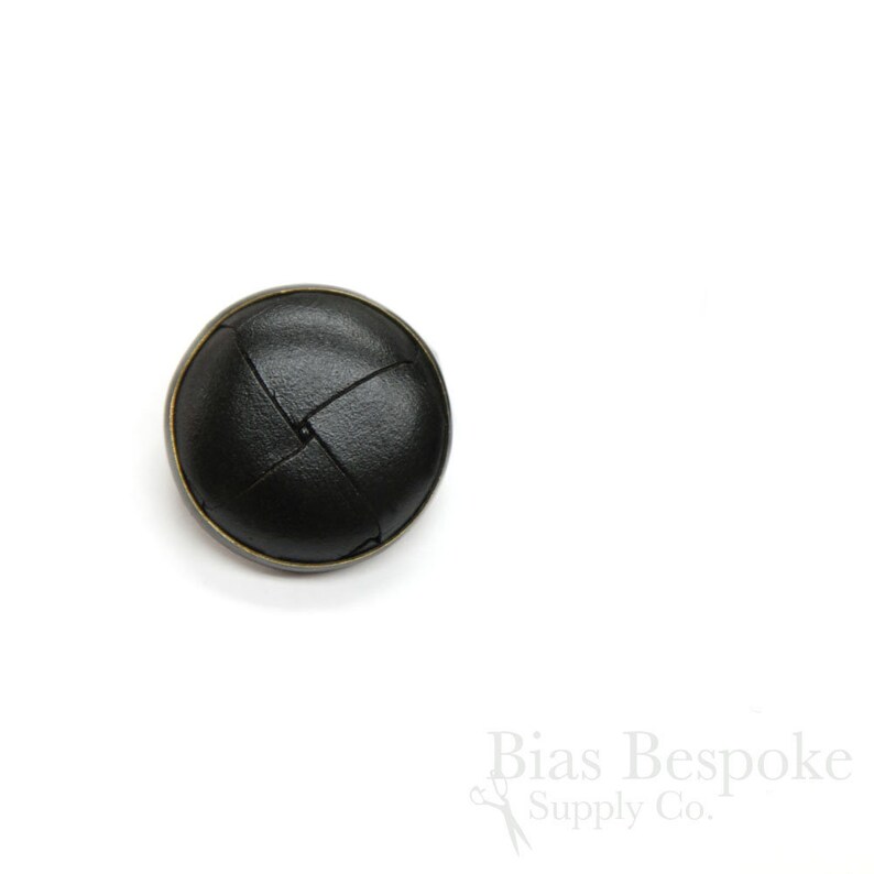 May include: Black leather button with a woven design and a brass rim.