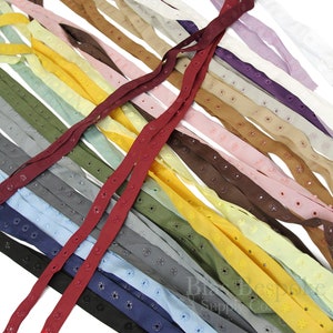 以下が含まれることがあります： 縫製プロジェクト用のアイレット付きカラフルなリボン詰め合わせ。リボンは、赤、黄、青、緑、茶色など、さまざまな色からお選びいただけます。