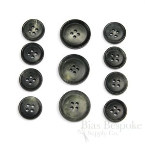 Könnte beinhalten: Satz von zehn schwarzen und grünen Hornknöpfen mit jeweils vier Löchern. Die Knöpfe sind in verschiedenen Größen.