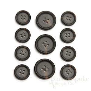 May include: Set of ten brown and black buttons with four holes each. The buttons are made of a mottled material that resembles horn.