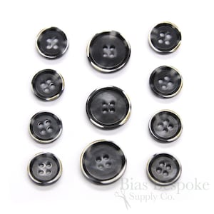 Puede incluir: Conjunto de 10 botones con estampado en blanco y negro con ribete dorado. Los botones tienen cuatro agujeros cada uno.