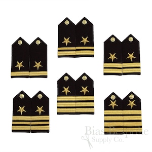 May include: A collection of navy blue shoulder boards with gold star and stripe details. The epaulettes feature gold stars and stripes, indicating rank. The image showcases various military insignia, suitable for uniforms or collectibles.
