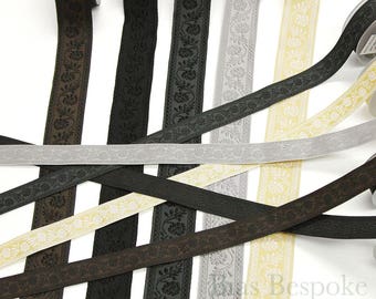 May include: Assortment of black, brown, and cream colored ribbon trim with a floral pattern. The ribbon trim is approximately 1 inch wide.