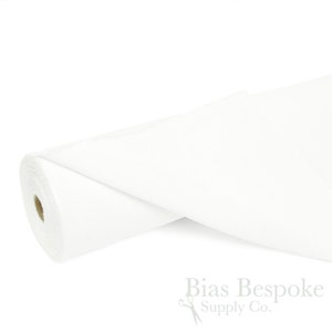 May include: A roll of white fabric, partially unrolled, against a white background. The fabric appears to be a solid color and is tightly rolled. The text "Bias Bespoke Supply Co." is visible in the lower right corner.
