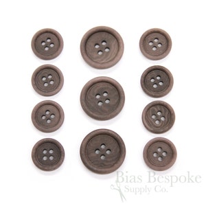 May include: Set of ten brown wooden buttons, each with four holes. The buttons are arranged in three rows, with the largest buttons at the top and the smallest buttons at the bottom.
