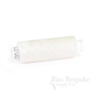 May include: A spool of white thread for sewing, with a label that reads "Made in USA 100% Cotton 40 wt 500 yd."