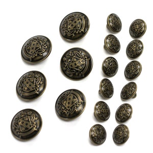 May include: A set of 17 antique gold-toned buttons with a decorative crest design. The buttons are round and have a raised design.