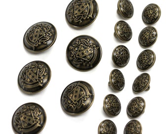 May include: A set of 17 antique gold-toned buttons with a decorative crest design. The buttons are round and have a raised design.