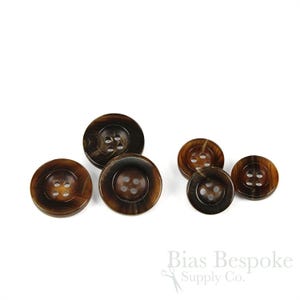 May include: Set of five brown horn buttons with four holes each. The buttons are different sizes and have a mottled brown color.