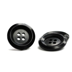 May include: Four black plastic buttons with four holes each. The buttons are round and have a raised edge.