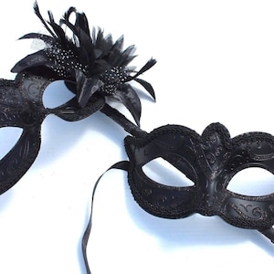 Impressionantes máscaras pretas para casais dele e dela em um bastão preto