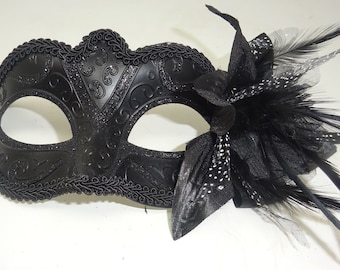 May include: A black masquerade mask with a decorative design and a black feather accent.