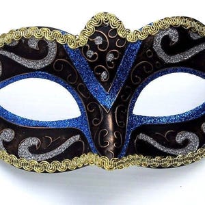 Op de afbeelding: Een zwart en zilveren masker voor een maskerade met blauwe glitteraccenten en gouden rand. Het masker heeft een traditioneel Venetiaans ontwerp met ingewikkelde details.