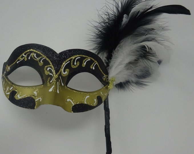 Hand Held Glittering Black White and Gold Masquerade Mask on a Black Stick with Jewel and Feathers
