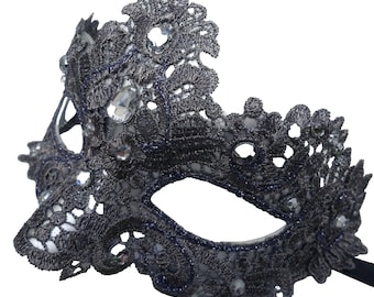 May include: A silver and black masquerade mask with intricate lace detailing and rhinestones.