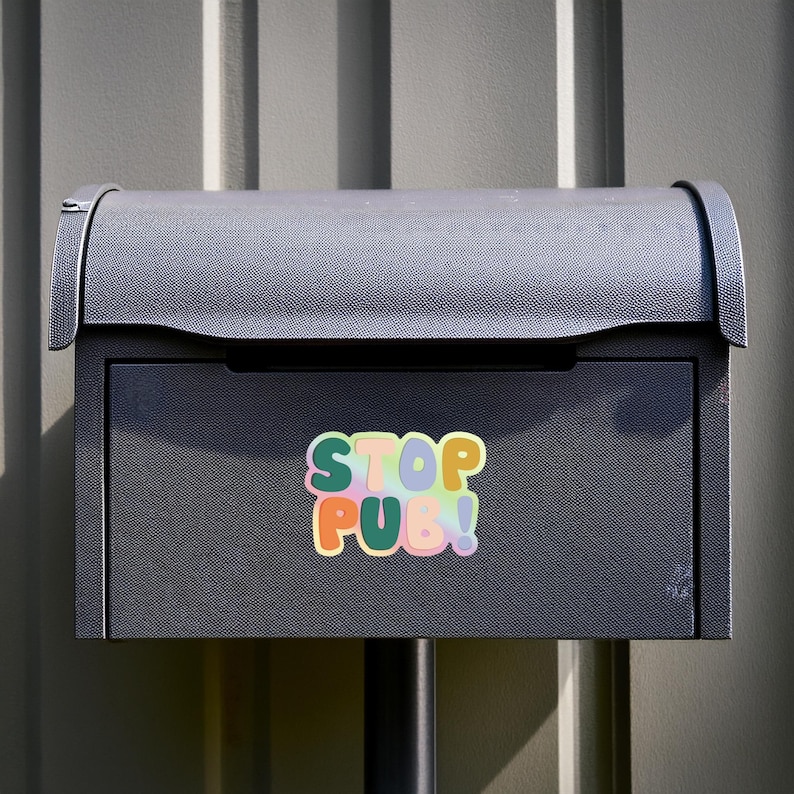 May include: A dark gray metal mailbox featuring a rectangular sticker with rounded edges. The sticker displays the text STOP PUB! in a bold, multi-colored, bubble-style font against a soft, pastel-toned, gradient background with a white border.