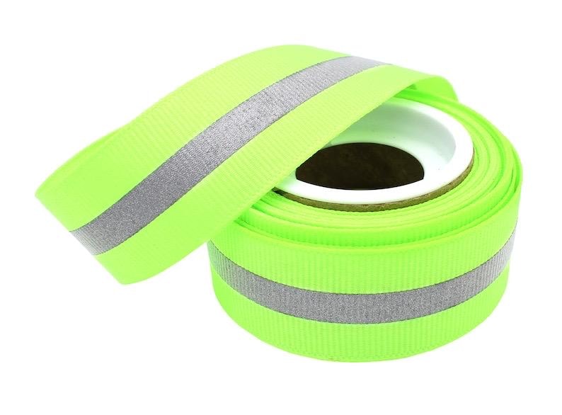 May include: A roll of lime green ribbon with a silver reflective stripe. The ribbon is rolled up and ready to be used for crafts, decorations, or other projects.