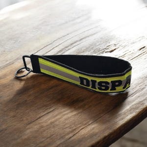 May include: Black and yellow key chain with the word "DISPATCH" printed on it.
