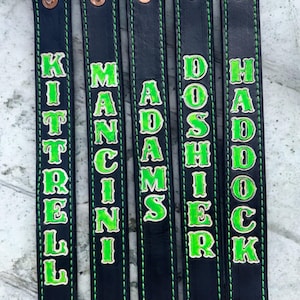May include: Five black leather straps with green stitching and white lettering. The straps are labelled "Kittrell", "Mancini", "Adams", "Doshier", and "Haddock".