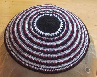 May include: A black, white, and red crocheted kippah with a circular design.