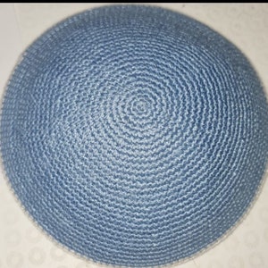 May include: A light blue kippah with a white trim. The kippah is made of a woven fabric and is circular in shape.