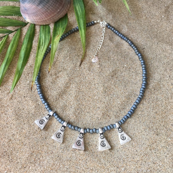 Collana Beachcomber: Collana con perle di vetro grigio argento metallizzato opaco e ciondoli a triangolo con stampa di onde