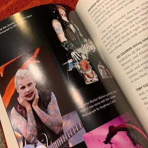 Puede incluir: Una p&aacute;gina doble de un libro con im&aacute;genes de m&uacute;sicos. Una foto muestra a una persona con maquillaje blanco, tatuajes y una guitarra. El texto dice "Early Rob Zombie" y "Photograph by Bill."